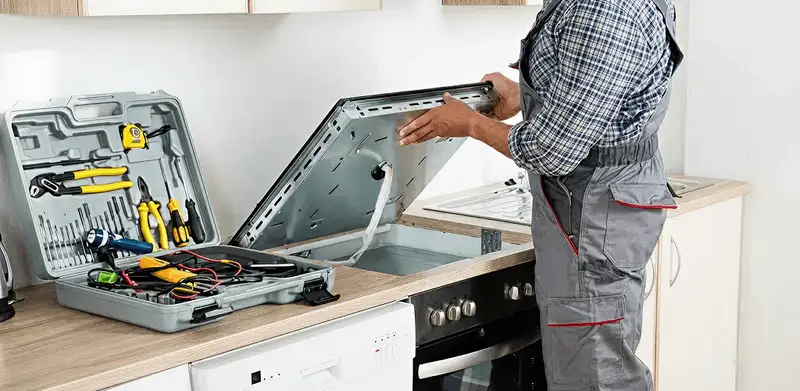 Handyman repairing a cooktop and checking wiring connections in Fresno, CA