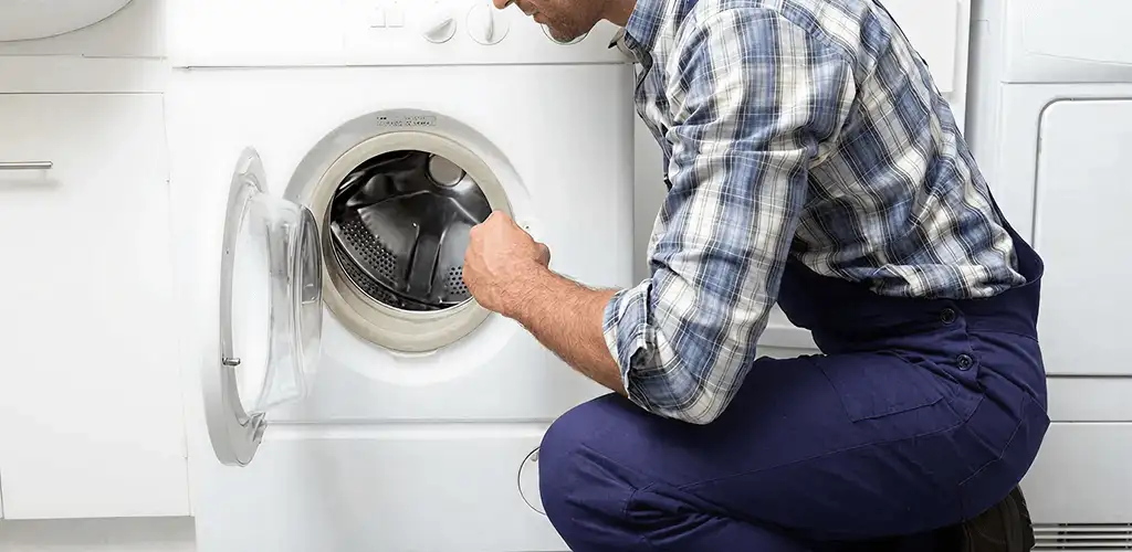 Handyman inspecting a dryer drum and internal parts for repair in Fresno, CA