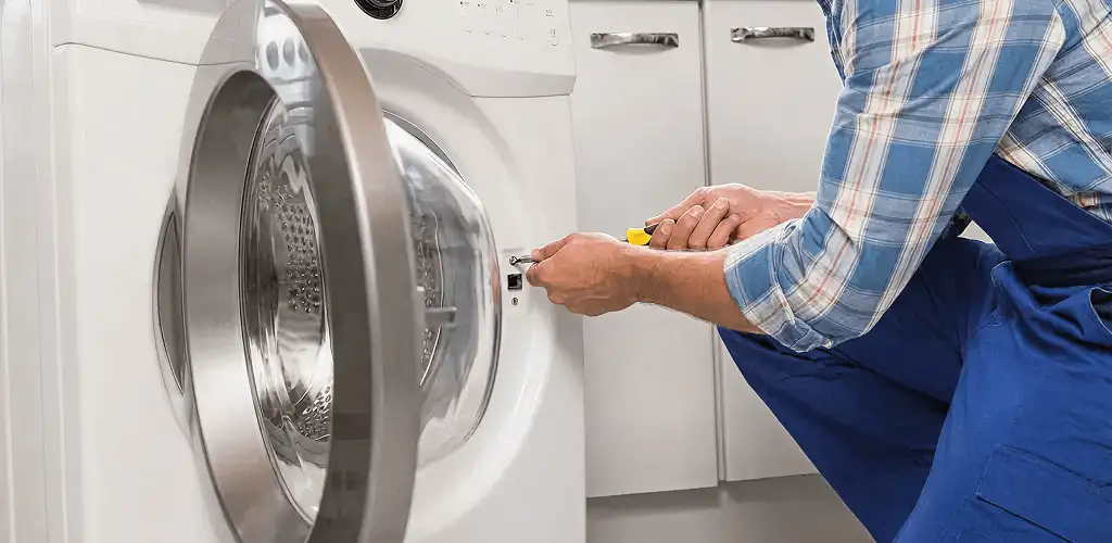 Handyman repairing a clothes dryer and checking electrical connections in Fresno, CA