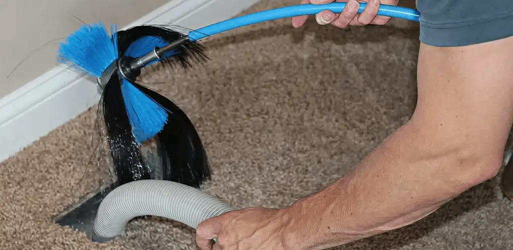 Dryer vent cleaning technician brushing lint from a vent line in Fresno, CA