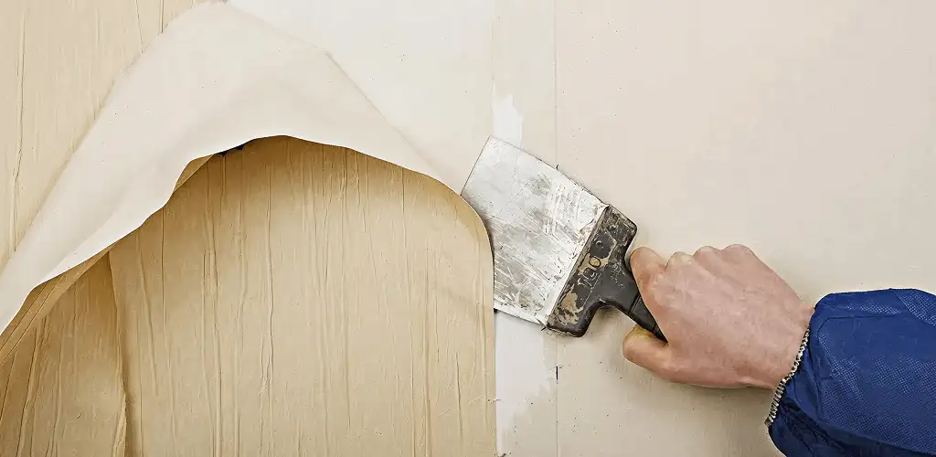 Handyman removing wallpaper with a scraper for wall preparation in Fresno, CA