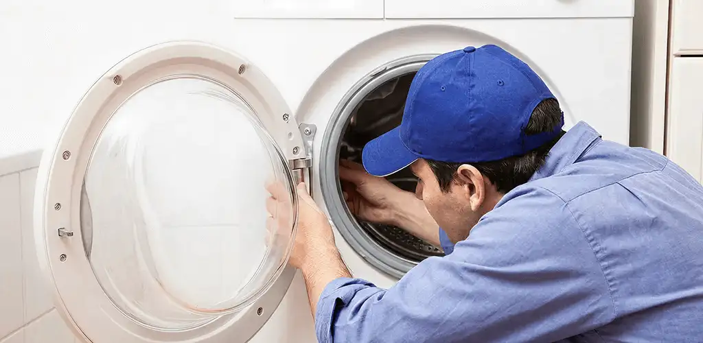 Washing machine repair handyman inspecting a front-load washer drum in Fresno, CA