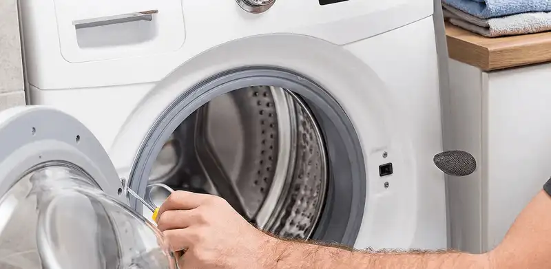 Handyman repairing a front-load washing machine and inspecting the drum in Fresno, CA