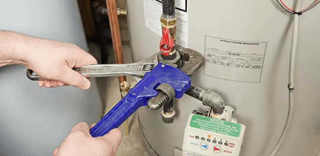 Water heater repair technician tightening the shutoff valve and supply line in Fresno, CA
